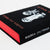 A close-up of a book titled 'Hidden Pictures' with a black cover, white illustration, and bright red page edges visible on a white background.