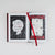 An open book on a light gray background, showing two full-color original cover options for 'Hidden Pictures.' The pages are mostly white with black sketch-style artwork and bold red title text, and a red satin ribbon bookmark runs down the center.