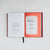 An open hardcover book laid flat on a light gray background. The left page is white with black text, and the right page has a red signature page, including a signature from Jason Rekulak.
